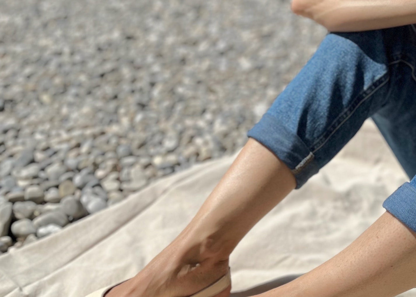 Eine Frau an der Isar trägt cremeweiße Peep-Toe-Ballerinas aus Leder