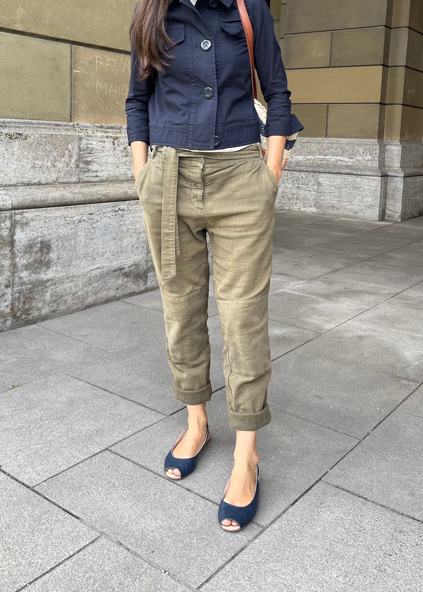 Frau trägt dunkelblaue Peeptoe-Ballerinas und eine Jacke in derselben Farbe.