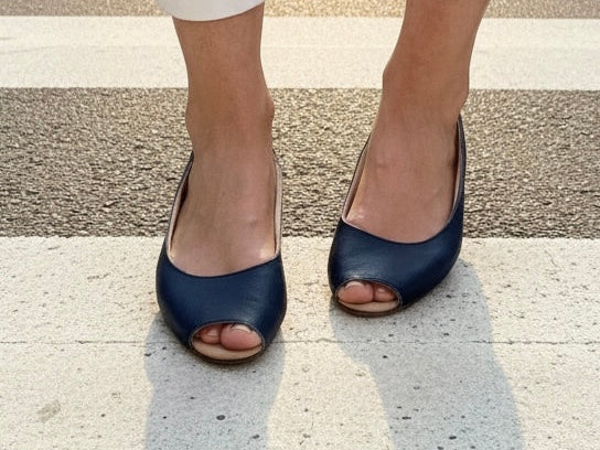 Frau trägt dunkelblaue Peeptoe-Ballerinas aus Leder.