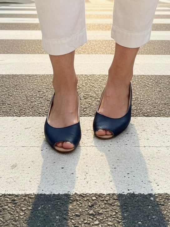 Frau trägt dunkelblaue Peeptoe-Ballerinas aus Leder.